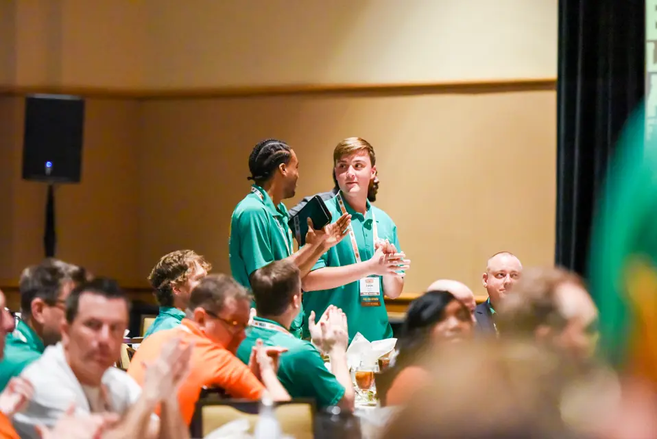 Team members in College HUNKS green polos applauding during a reunion session