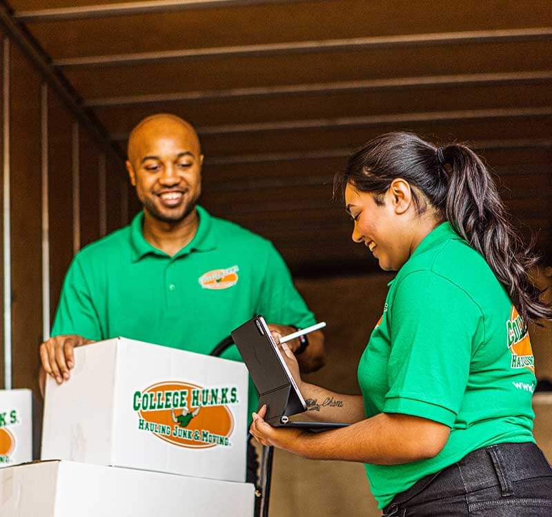 College Hunks Hauling Junk&reg; crew member reviewing a checklist with a customer at the door