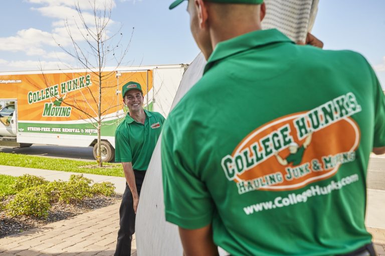 College HUNKS movers carrying furniture to a branded moving truck at a residential job